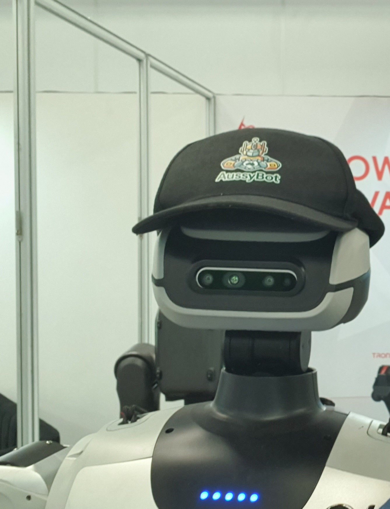 LimX Oli wearing an AussyBot cap on the RSS 2026 show floor